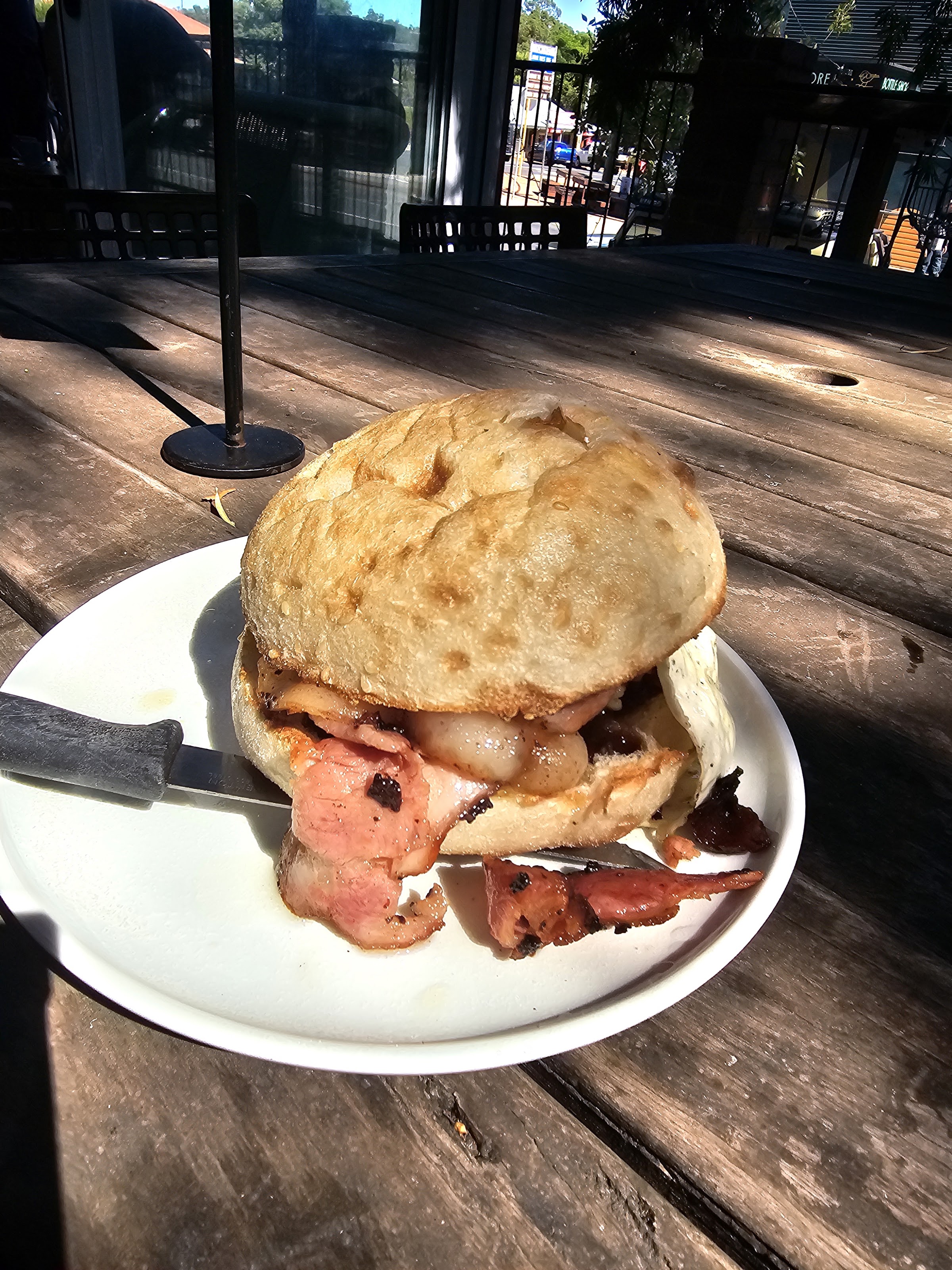 A bacon and egg roll on a sourdough bun on the timber deck