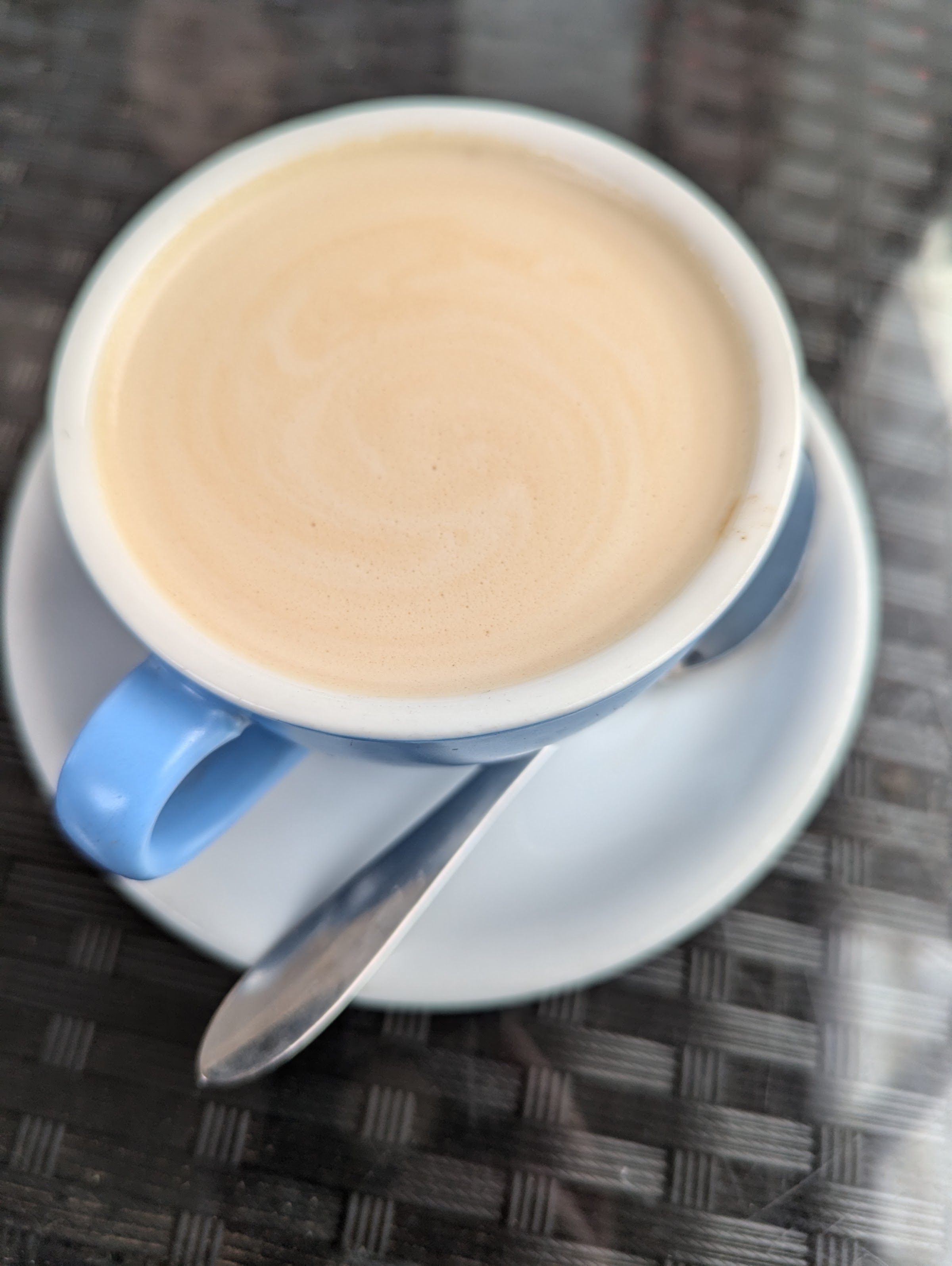 A flat white in a pale blue cup and saucer